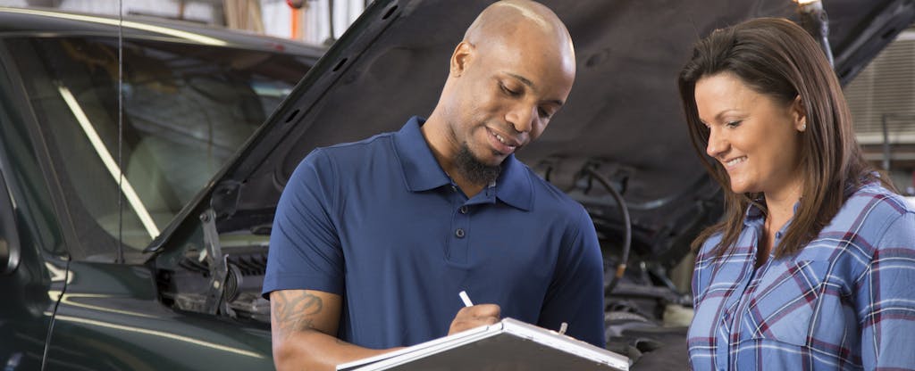 Mechanic explains vehicle repairs to customer in auto repair shop