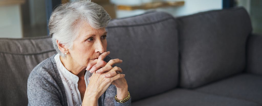 Woman sitting on a couch, looking thoughtful