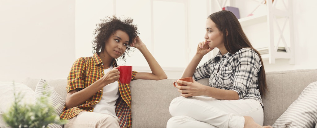 Two women sitting on a couch and having a conversation