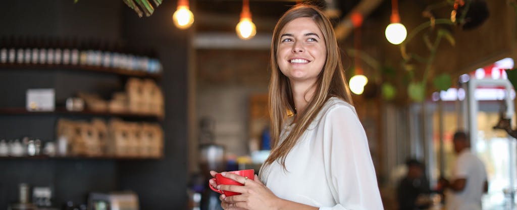 Woman standing in a coffee shop, smiling