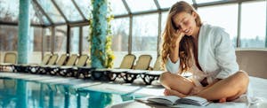 Young woman reading a book by the hotel pool