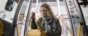 Woman looking through her bag as she's getting on a bus