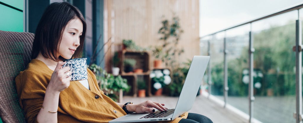 Young woman working on laptop on apartment balcony