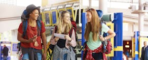 Three female friends in the airport going on a backpacking trip