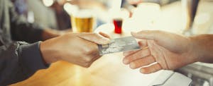 Woman presenting her prepaid card to pay at a restaurant bar