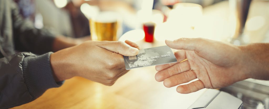 Woman presenting her prepaid card to pay at a restaurant bar