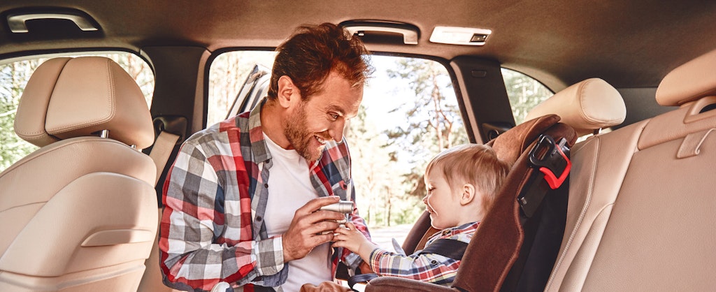 Father trying to entertain his baby boy who's sitting in a car seat