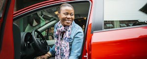 Woman in Red Car Smiling with Car Door Open