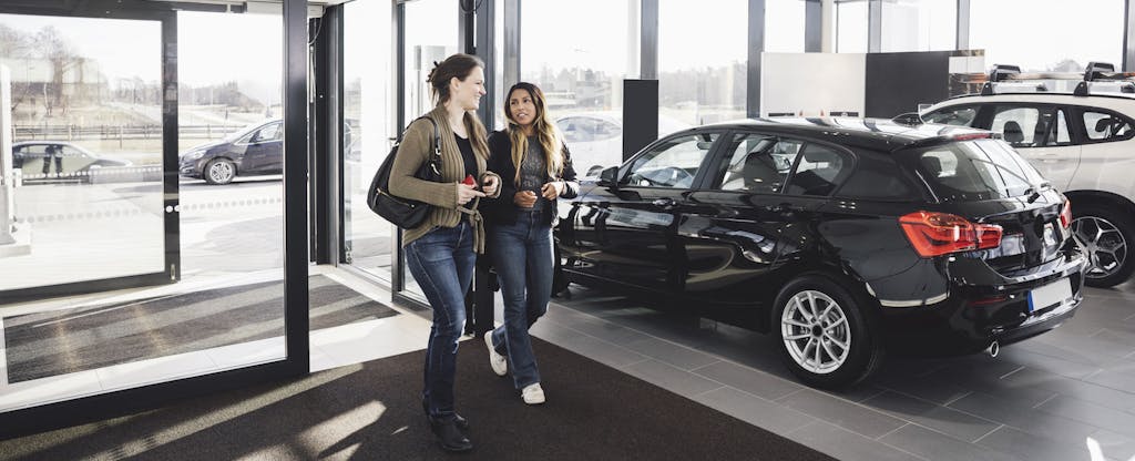 Two women walking into a car dealership, ready to shop for a new car