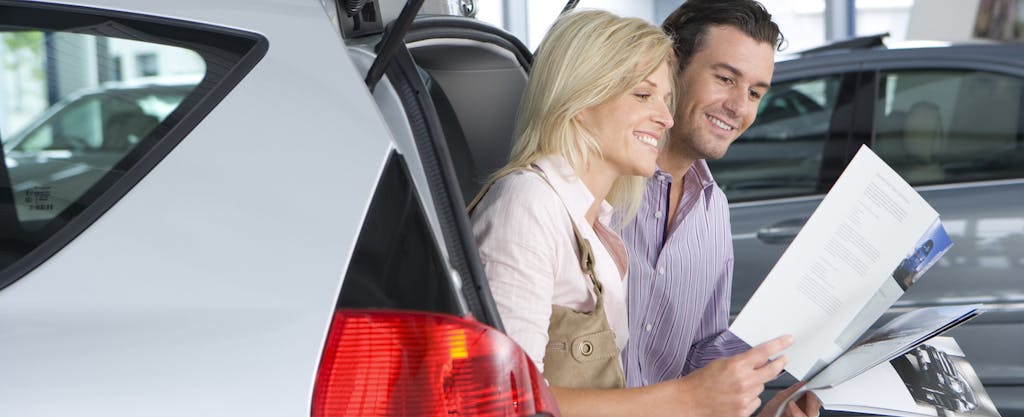 Couple looking at new car brochure and thinking about how to negotiate a car lease