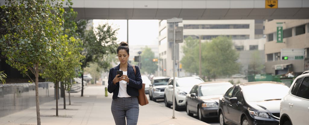 Woman walking down a street, looking at her phone
