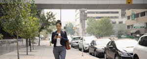 Woman walking down a street, looking at her phone