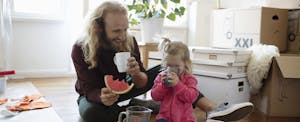 Father and daughter eating watermelon and drinking water in living room