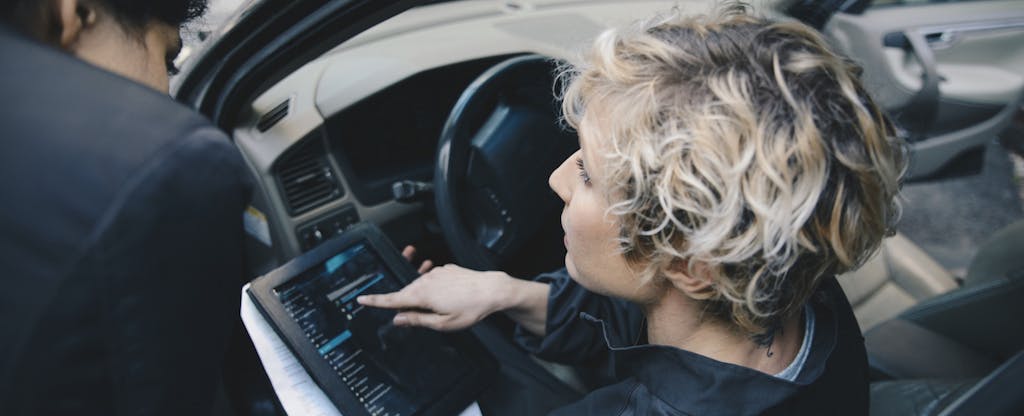 Woman looking at a tablet as she sits in her car