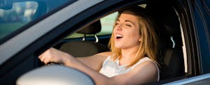Woman driving her car, singing and smiling