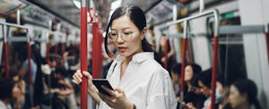 Young businesswoman looking at smartphone while riding on subway