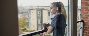 Young woman drinking coffee on apartment balcony