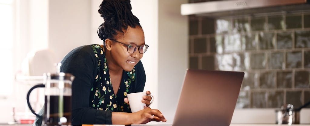 Young woman in her kitchen drinking coffee and reading over tax form 1099-INT