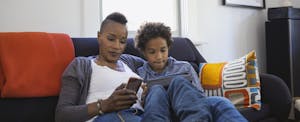 Woman sitting on couch with son, using her smartphone to research states with no income tax