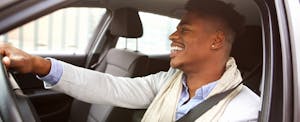 Smiling young African American man driving car