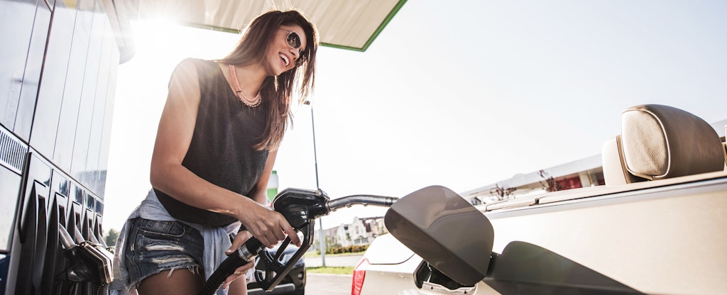 Woman smiling as she pumps gas at a gas station