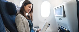 Woman on airplane reading a magazine
