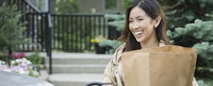 Woman standing outside, unloading groceries from her car and smiling