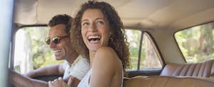 Man and woman sitting in a car together, laughing