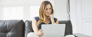 Woman using laptop on sofa to look up Tesla financing