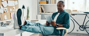 Young man in home office researching loans on his tablet