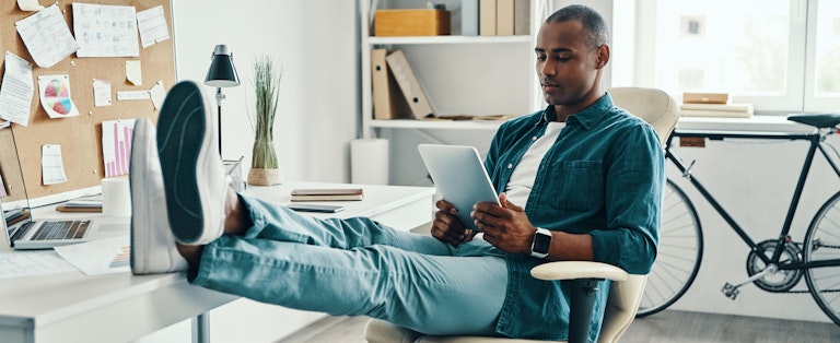 Young man in home office researching loans on his tablet