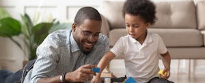 Father and toddler son playing with blocks in their living room