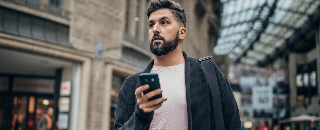 Young man walking in the city and holding phone