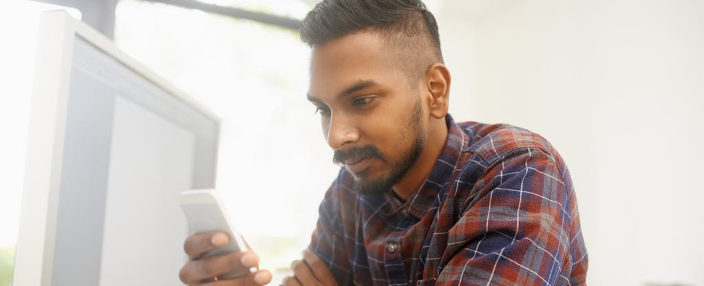 Man using his smartphone while sitting at his desk in the office