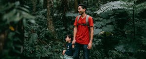 Father and his little girl hiking in lush green rainforest