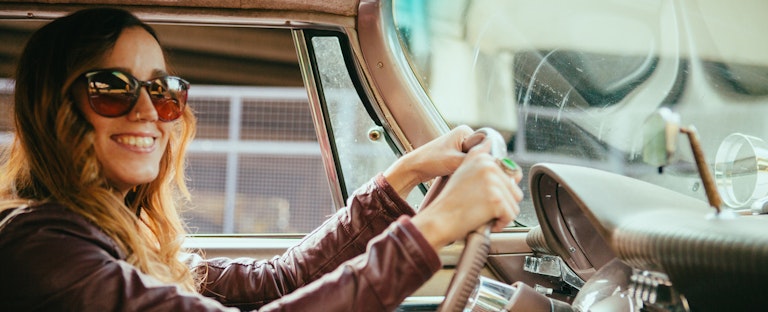 Woman driving a car and smiling on a sunny day