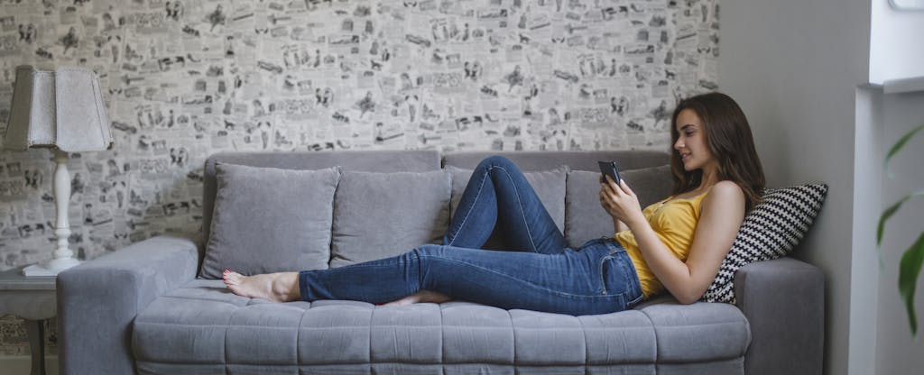 Woman lounging on her couch, using her smartphone