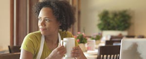 Woman sitting at restaurant table holding a cup of coffee