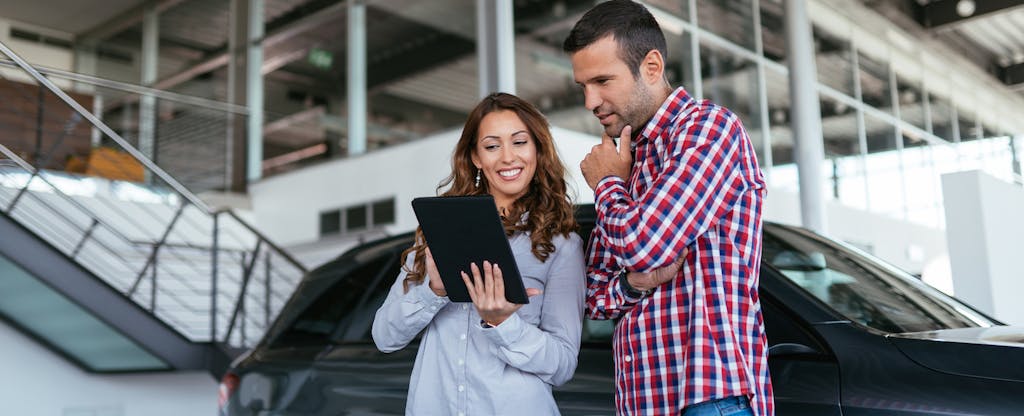 Young couple at car dealership looking at new car together