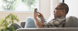 Man sitting on his couch at home in his living room, using his phone to read a review of Bright Lending