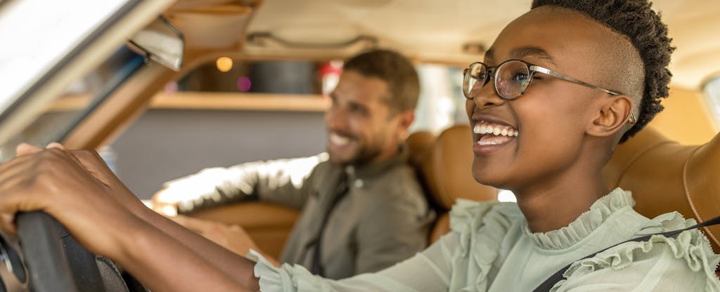 Young, smiling couple in car talking about full coverage auto insurance