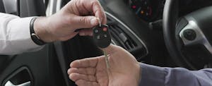 Close up of two hands - car salesman handing keys to car buyer