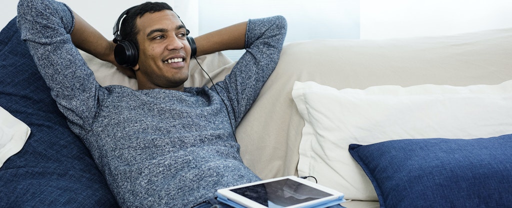 Man sitting on couch wearing headphones, thinking about what credit score he needs to get a personal loan