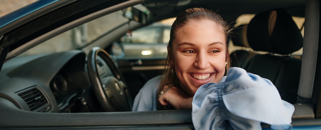 Young woman sitting in car, thinking about what types of auto insurance she should get