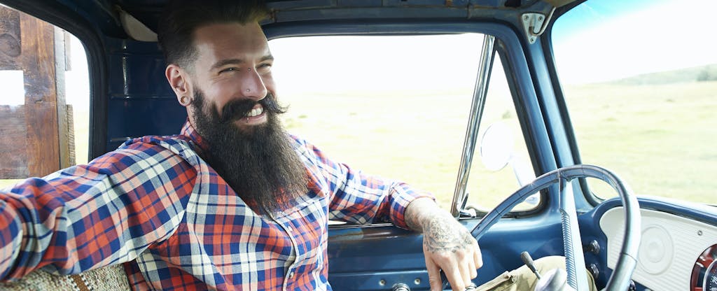Smiling bearded man sits in his truck that he bought with a golden 1 auto loan