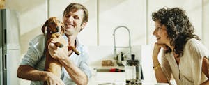 Couple sitting together in their kitchen, smiling and discussing opening a joint savings account