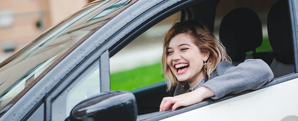 Smiling young woman driving her car that's insured with GEICO auto insurance