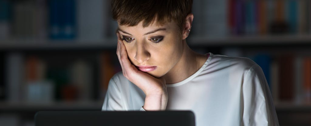 una mujer mira su laptop en la oscuridad