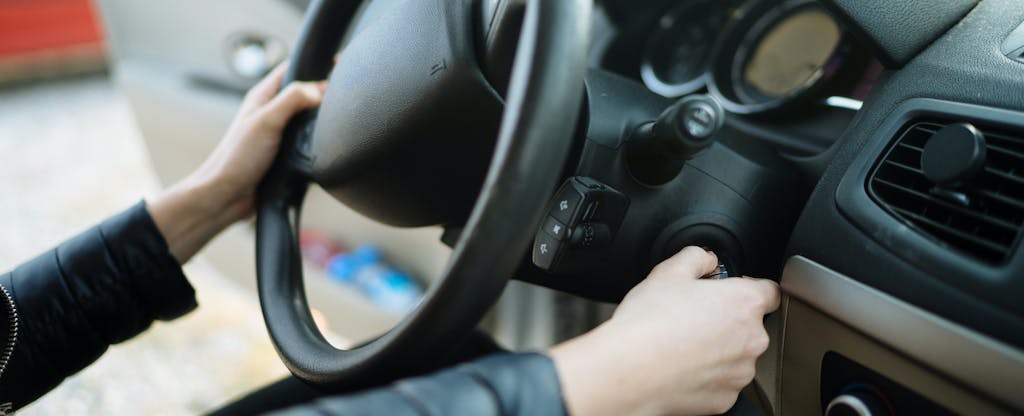 Close up of woman's hands on the steering wheel of a car at a car dealership