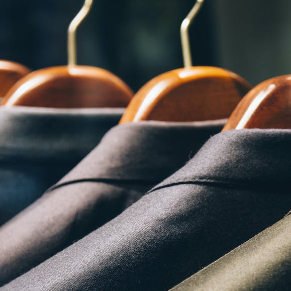 Men's suits hanging in a row on clothing rack